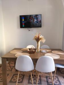 einen Esstisch mit weißen Stühlen und einen TV an der Wand in der Unterkunft Appartamento Porta Lecce in Brindisi