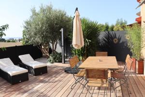 un patio con mesa, sillas y sombrilla en Le petit Sud, en Carqueiranne