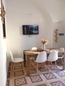 ein Esszimmer mit einem Holztisch und weißen Stühlen in der Unterkunft Appartamento Porta Lecce in Brindisi