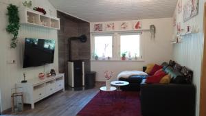 sala de estar con sofá y TV en Ferienhaus Bea, en Buchholz - Aller