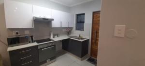 - une cuisine avec des placards noirs et blancs et un évier dans l'établissement Two Bedroom Apartment, à Durban