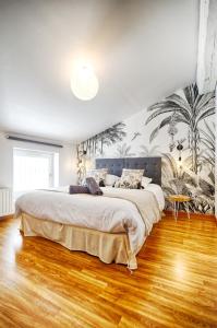 1 dormitorio con 1 cama grande y un mural de palmeras en Le Raphaël, en Le Puy en Velay