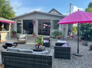 a patio with couches and a pink umbrella at The Croft Accommodation in Gamrie