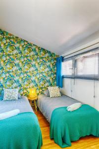 two beds in a room with blue and yellow wallpaper at Le Raphaël in Le Puy en Velay