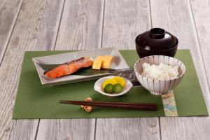 un plato de sushi y un tazón de arroz y palillos chinos en 本庄バニラリゾート, en Ishigami