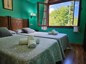 2 camas en una habitación con paredes verdes y ventana en Hotel Rural Casa Migio, en Urbiés