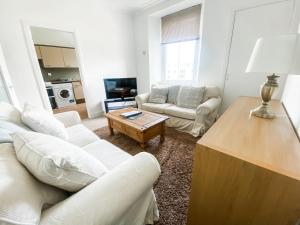 una sala de estar con 2 sofás blancos y una mesa. en Pipelands Road, en St Andrews
