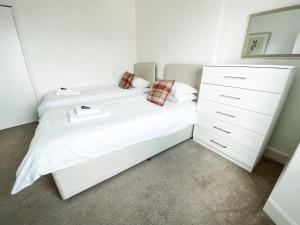 1 dormitorio con cama blanca y vestidor en Pipelands Road, en St Andrews