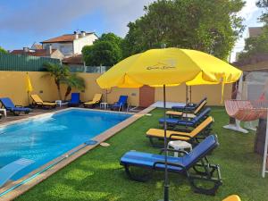 uma piscina com espreguiçadeiras e um guarda-sol amarelo em Quinta Salinas - Puro Prazer em Aveiro