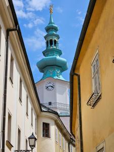 a building with a tower with a clock on it at NEW Design & High Standard Apt from 16th Century in Old Town in Bratislava