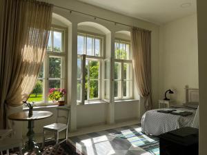 - une chambre avec des fenêtres, un lit et une table dans l'établissement Oleru muiža, 