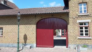 a red barn with a red door on a brick building at Boerderijwoning Elsloo in Elsloo