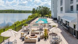 um pátio exterior com uma piscina, mesas e guarda-sóis em Crowne Plaza Ft Myers Gulf Coast, an IHG Hotel em Fort Myers