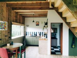 a room with a table and a kitchen with wooden ceilings at Olejarnia Godki in Jonkowo