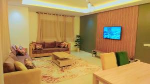 een woonkamer met een bank en een tv aan de muur bij Appartement Costa Bouznika in Bouznika