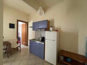 a kitchen with blue cabinets and a white refrigerator at ΑΤΕΛΙΟΥ ΣΤΟΥΝΤΙΟ in Vari