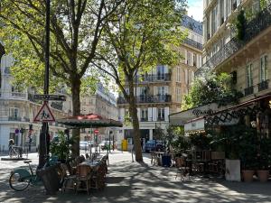 eine Stadtstraße mit Tischen, Stühlen und Gebäuden in der Unterkunft 70 sqm apartment in 75008 Paris in Paris