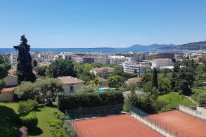 einen Tennisplatz mit einer Stadt im Hintergrund in der Unterkunft Juan les pins 2 pièces vue mer Résidence Eden Park in Juan-les-Pins