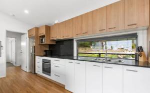 a kitchen with white cabinets and a large window at Top of the Bay in Arthurs Seat