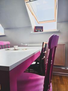 Una mesa con sillas moradas y una mesa con ventana. en Top Roof ApARTment, en Gdansk