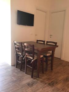 uma mesa de madeira com cadeiras e uma televisão na parede em THE RANCH Apartment 4 Capalbio em Pescia Romana