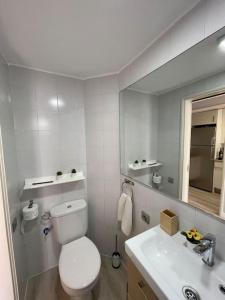 a white bathroom with a toilet and a sink at Apartamento Puerto Rico - Primera línea de playa in Mogán