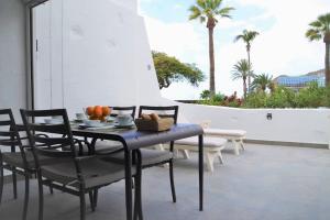 un tavolo e sedie su un patio con palme di Apartamento Puerto Rico - Primera línea de playa a Mogán