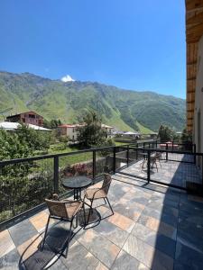 a balcony with a table and chairs and mountains at Guest House 15 in Kazbegi