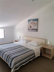 a bedroom with a bed with a striped blanket and two tables at Apartments Permida in Dramalj