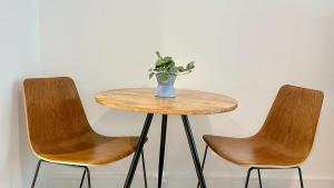 une table avec deux chaises et un vase avec une plante dans l'établissement Modern Regency Staycation, à Al Qurayyah