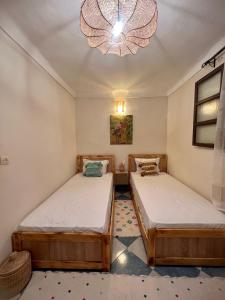 2 łóżka w pokoju z żyrandolem w obiekcie Peekaboo Hostel w Marakeszu