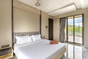 a bedroom with a large white bed and a window at SaffronStays Siesta by the River in Murbād