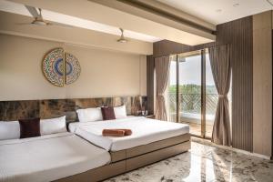 a bedroom with two beds and a balcony at SaffronStays Siesta by the River in Murbād