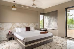 a bedroom with a large bed and a window at SaffronStays Siesta by the River in Murbād