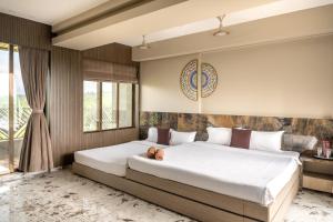 a bedroom with a large bed and a window at SaffronStays Siesta by the River in Murbād