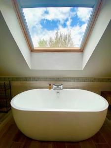 a large white bath tub in a bathroom with a skylight at Field View in Braunston