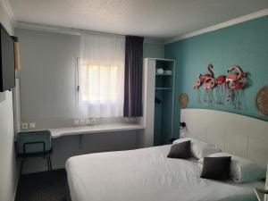a bedroom with a bed with a painting of flamingos on the wall at Kyriad Direct Arles in Arles