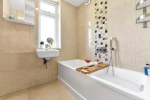 a bathroom with a tub and a sink and a glass of wine at 3BR home/Fast Wi-Fi/ Quiet road in Hither Green