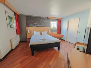 - une chambre avec un lit et une télévision dans l'établissement ibis Saint-Die, à Saint-Dié-des-Vosges