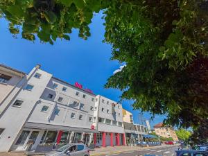 a white building on a street with cars parked in front at ibis Saint-Die in Saint Die