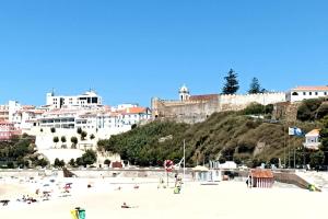 a group of people on a beach in front of a city at duArteLoft in Sines