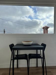 a bowl on a table with two chairs in front of a window at Ático casa de invitados Bluemoon in Las Lagunas