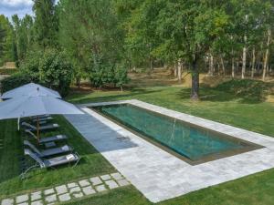 einen Blick über einen Pool mit Sonnenschirm und Stühlen in der Unterkunft Restful Holiday Home in Reggello with Swimming Pool in Reggello