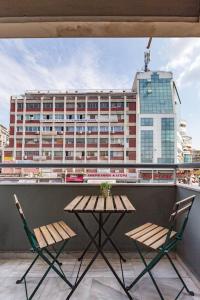 een tafel en 2 stoelen op een balkon met een gebouw bij Sunny studio apartment in Thessaloniki city center in Thessaloniki