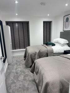 a bedroom with two beds and two windows at 4-Level Luxury 2 Bedroom House Sleeps 6, Rooftop, Harry P & Free Parking in Watford