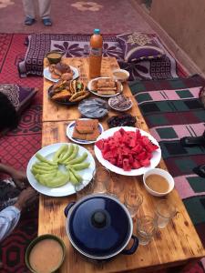 una mesa de madera con platos de comida. en Mhamid camp activités en Mhamid