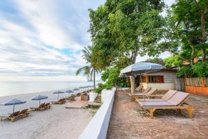 una fila di sedie e ombrelloni sulla spiaggia di Veranda Lodge a Hua Hin