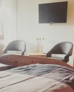 a bedroom with two chairs and a tv on the wall at Ferienwohnung Funk in Müllenbach
