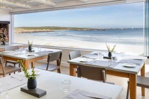 una sala da pranzo con tavoli e vista sulla spiaggia di Paternoster Dunes Boutique Guesthouse a Paternoster