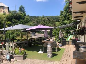 un patio con mesas y sombrillas en el césped en Bar Hotel Restaurant le Margeriaz, en Les Déserts